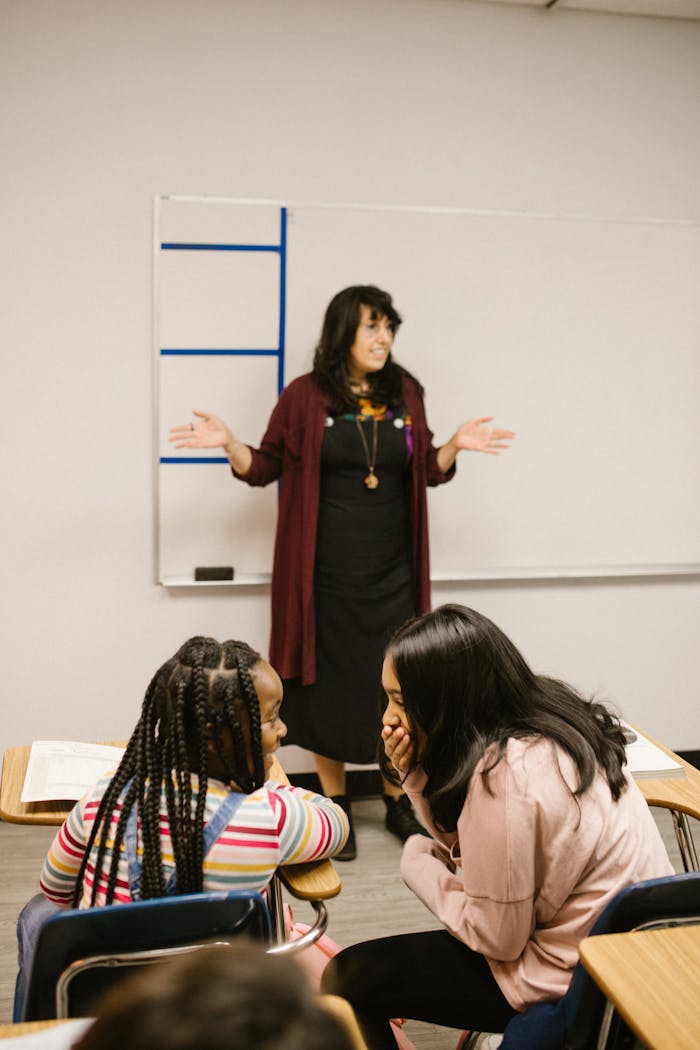 Teacher leading classroom discussion with students at their desks.