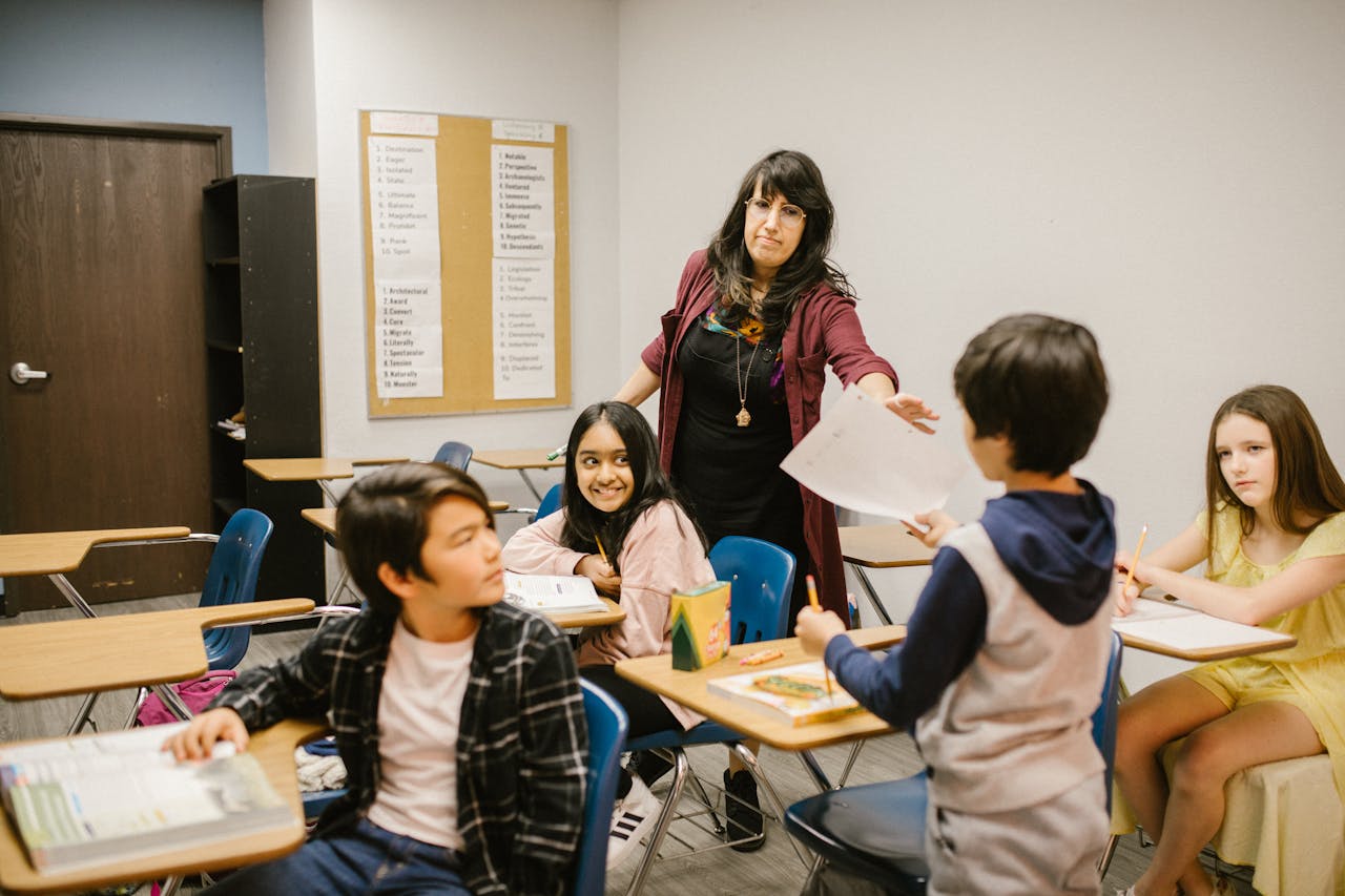Children interacting with a female teacher in a classroom setting, promoting education and diversity.